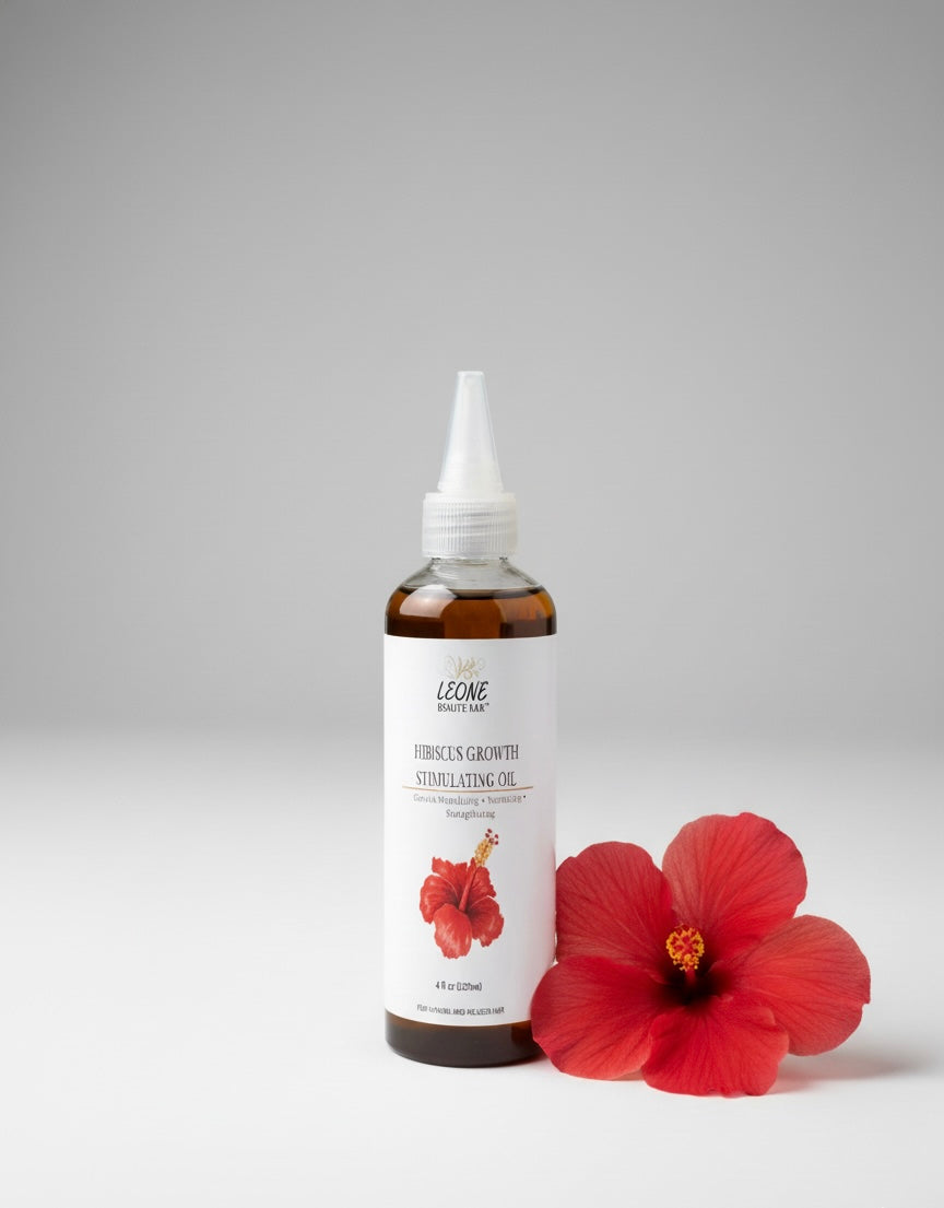 Bottle of Leone hibiscus stimulating growth oil product with a hibiscus flower on a gray background