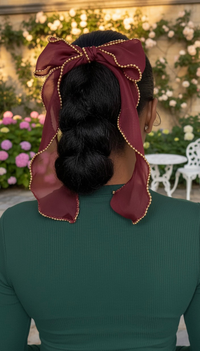 Person with a hair bow in a bun, wearing a green top, against a floral background.
