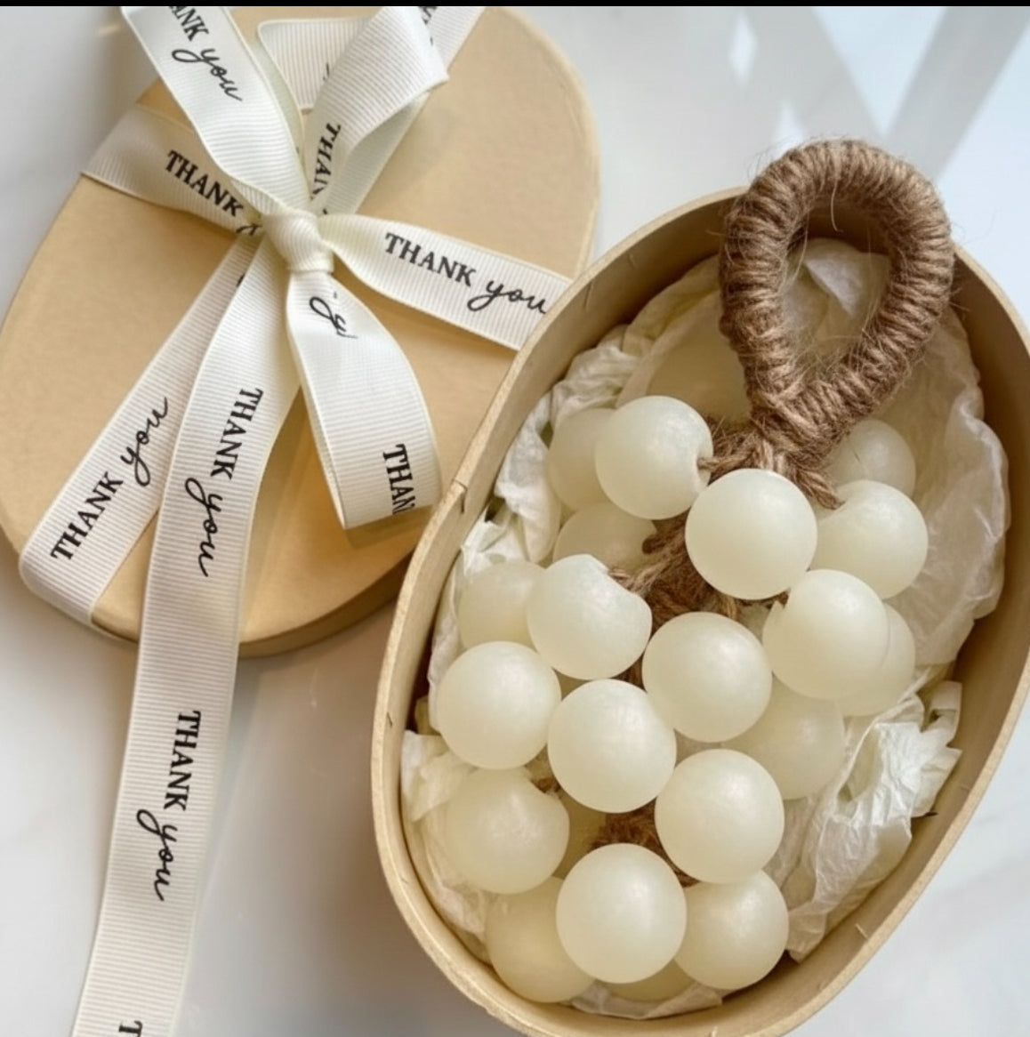 Decorative box with white grapevine  soap and a 'thank you' ribbon on a light background