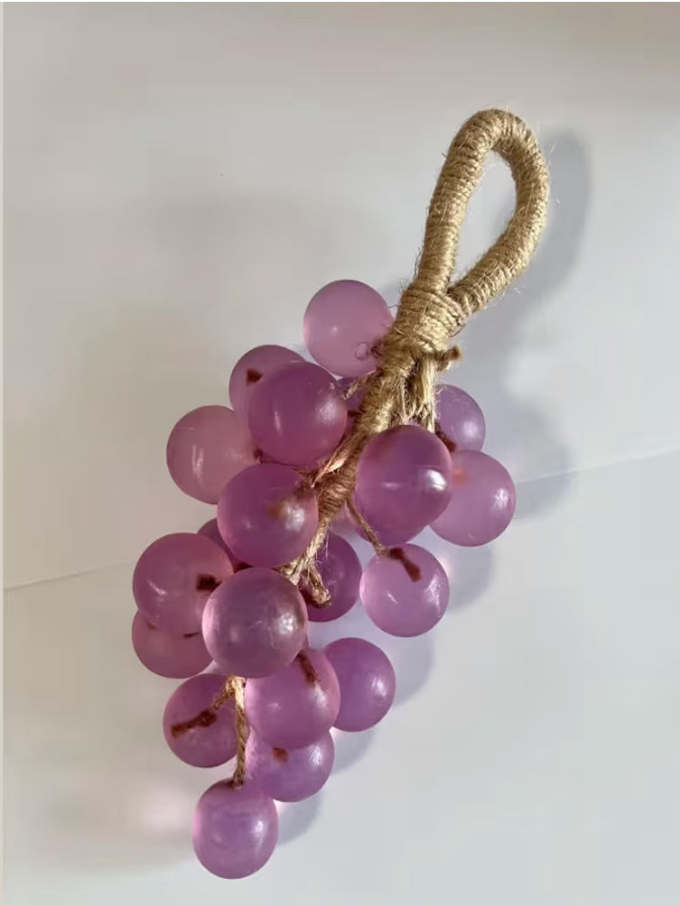 Decorative purple grape bunch with a natural fiber handle on a white background