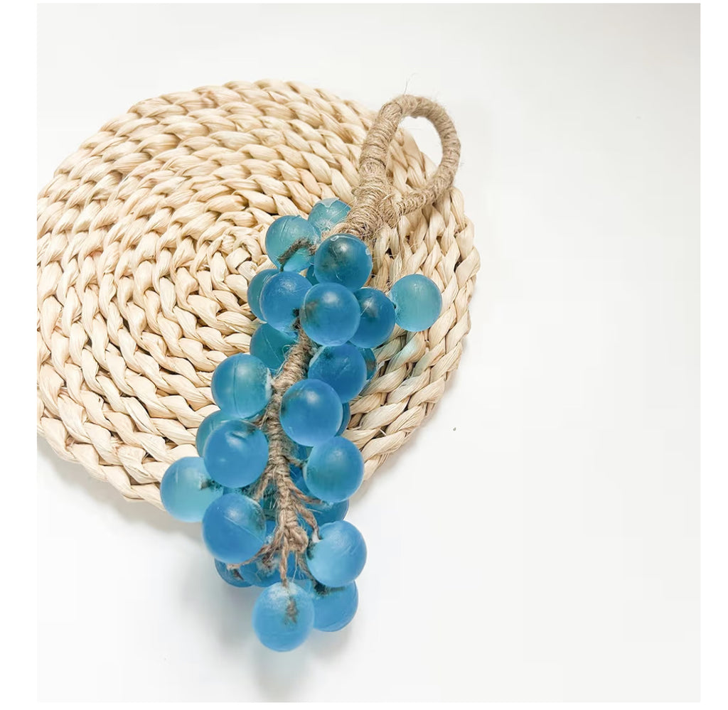 Blue decorative grape soap on a woven mat with a white background