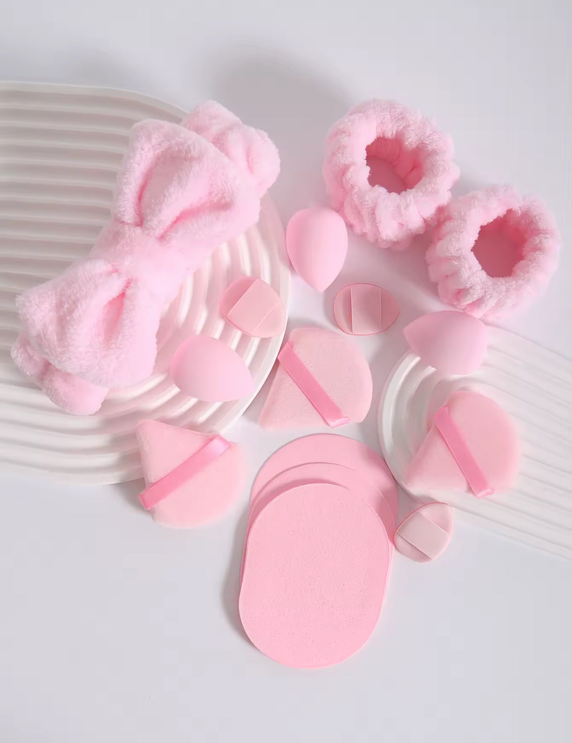 Pink bath accessories including a scrubber, loofah, and bath mitt on a white background