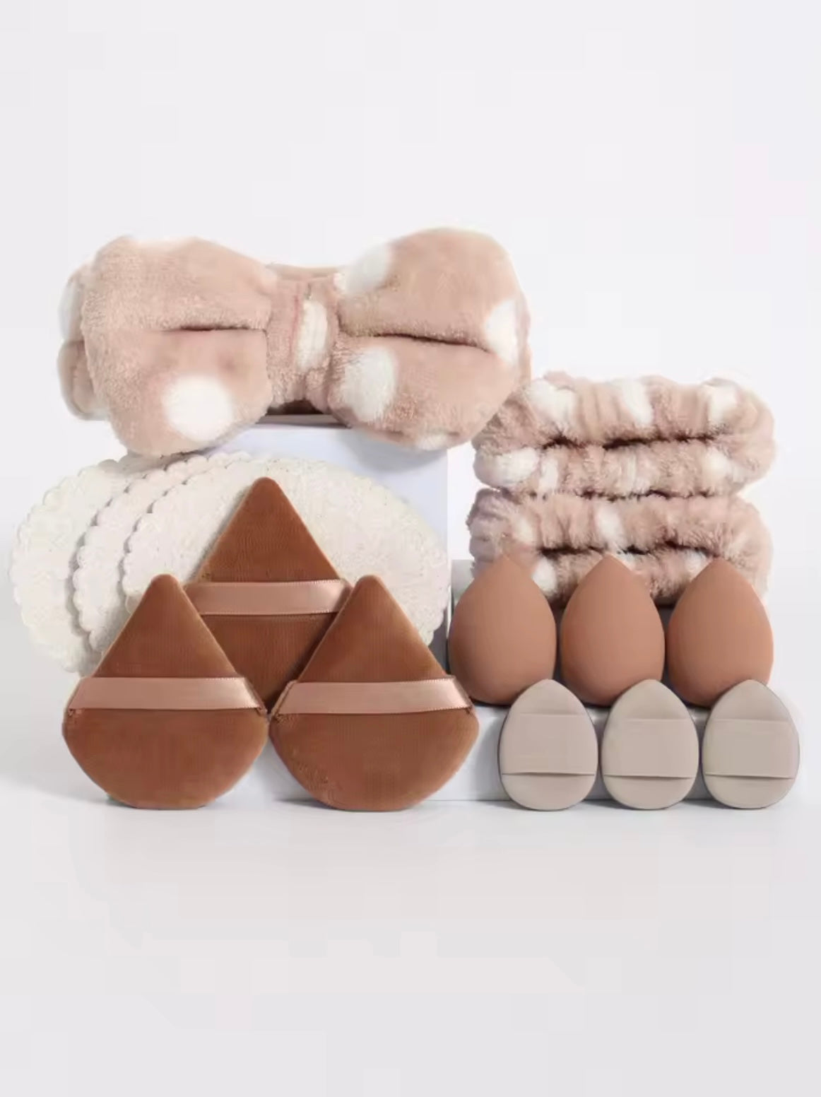 Set of brown makeup sponges and a bow on a white background