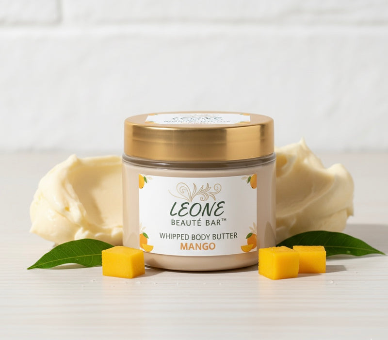 LEONE BEAUTE BAR whipped body butter container with mango pieces and leaves on a light background