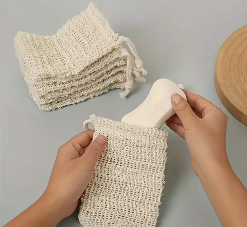 Hands holding a beige woven bag with more bags stacked in the background on a gray surface.